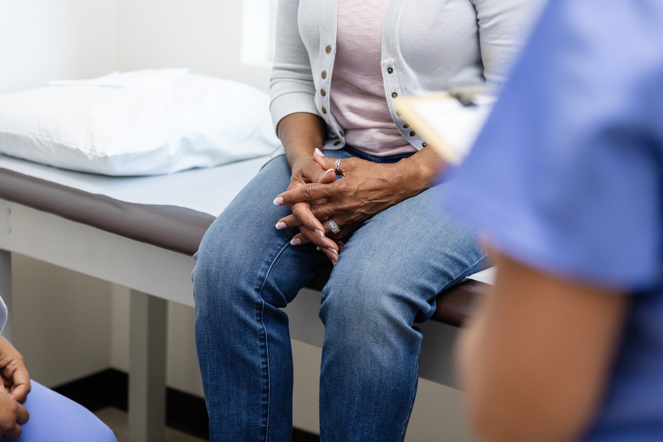 senior woman clasps hands during discussion with medical personnel